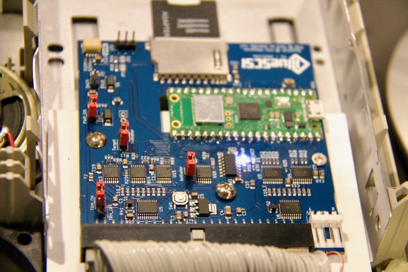 BlueSCSI board with a Raspberry Pi Pico installed inside a vintage Macintosh drive bay